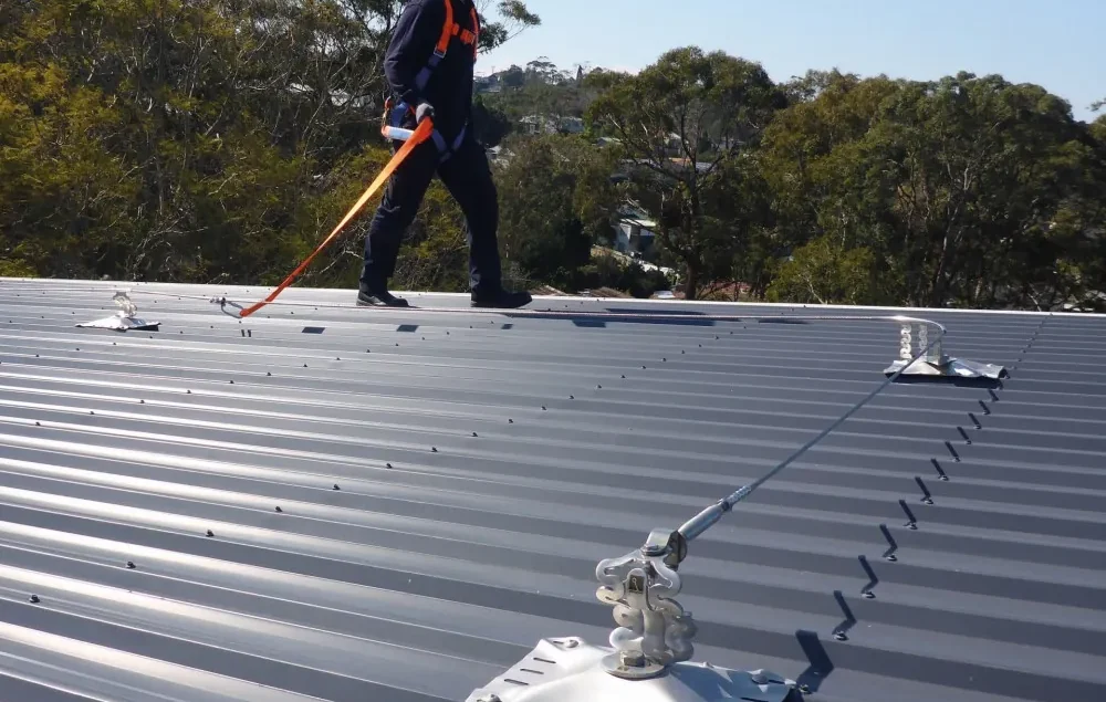 Trabajador con arnés junto a una línea de vida horizontal instalada en una cubierta metálica